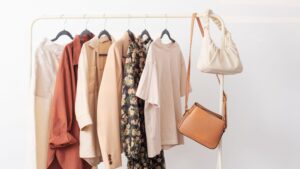 Rack de ropa con prendas cápsula en tonos tierra y neutros, incluyendo blusas, chaquetas, faldas y bolsos, ejemplo visual del método 3-3-3.